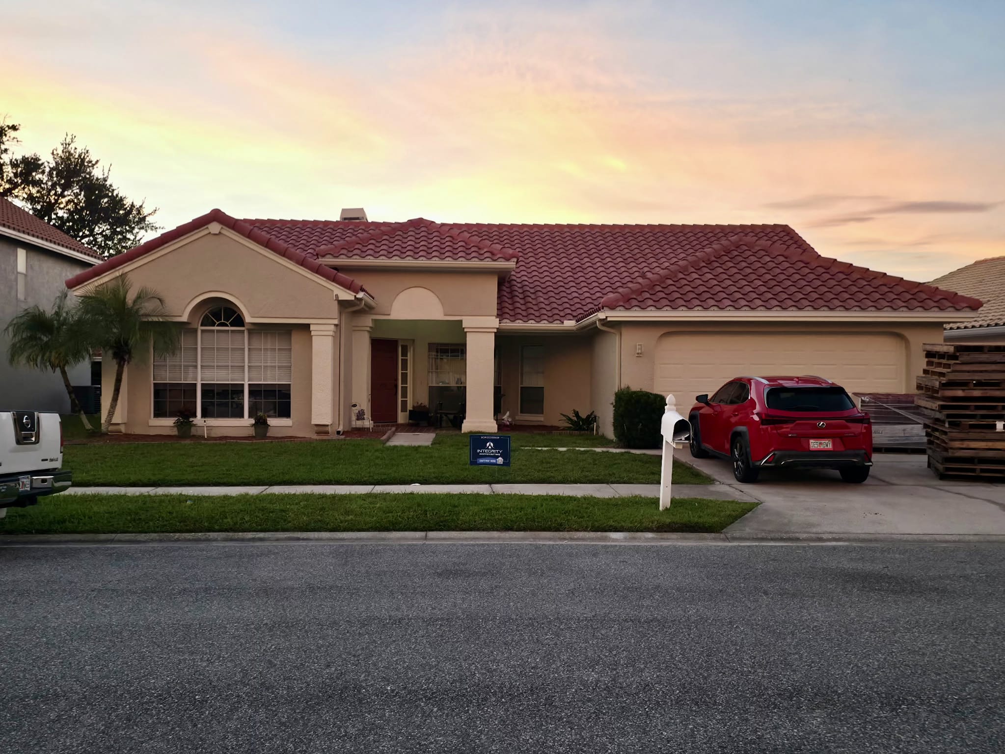 Front exterior view of a Florida single-story home with a newly installed red tile roof at sunset, showing the driveway, garage, and completed residential roof replacement.