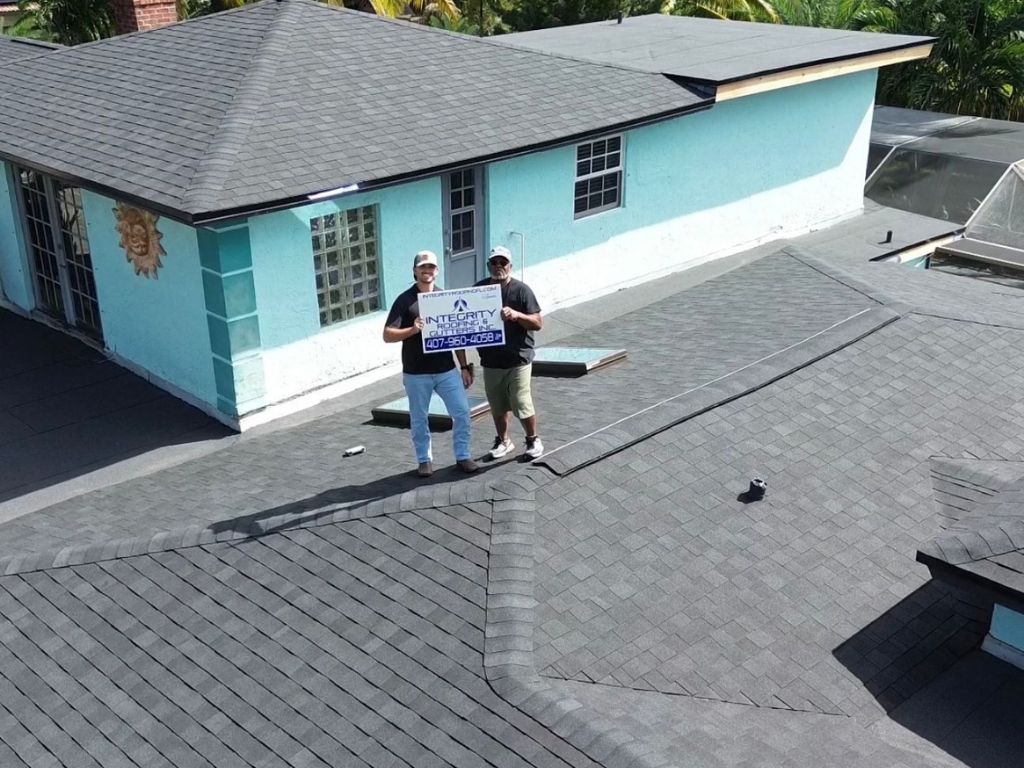 Roofing contractors from Integrity Roofing standing on a newly installed asphalt shingle roof during inspection.