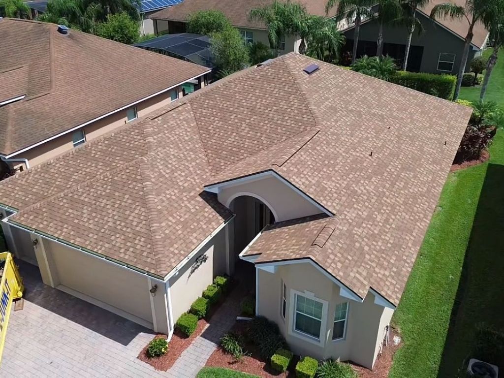 Aerial view of a residential home with freshly installed asphalt shingles roof, showcasing quality roof replacement services by Integrity Roofing.
