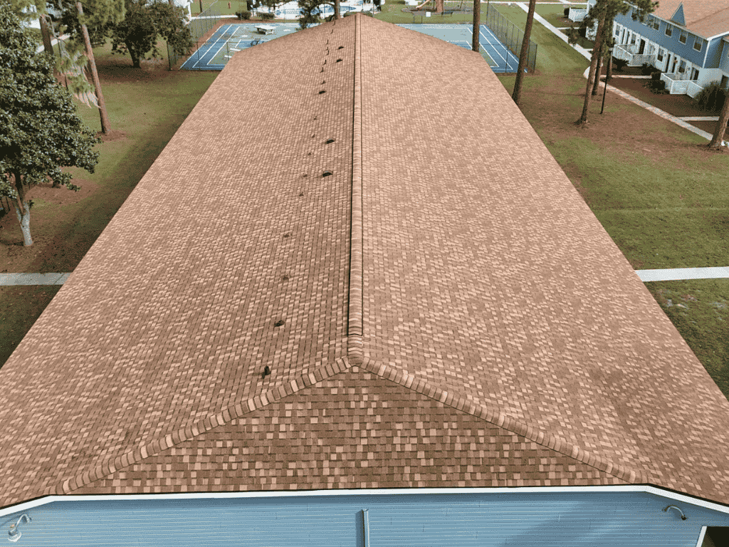 Aerial view of a well-maintained roof showing shingle patterns and roofing details. The image showcases the entire length of the roof with no visible damage, surrounded by greenery and tennis courts.